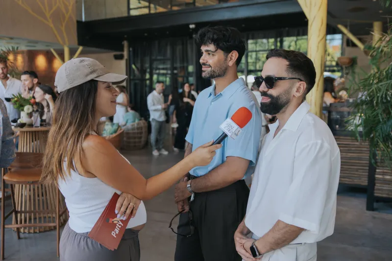 מראיינת של PartyTalk מראיינת שני אורחים עם מיקרופון באירוע - ראיון אורחים אחרי תחקיר מקדים