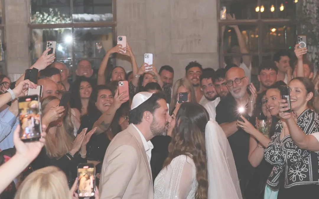 חתן וכלה מתנשקים מוקפים באורחים שמצלמים - 4 דברים שחשוב לדעת על יום החתונה